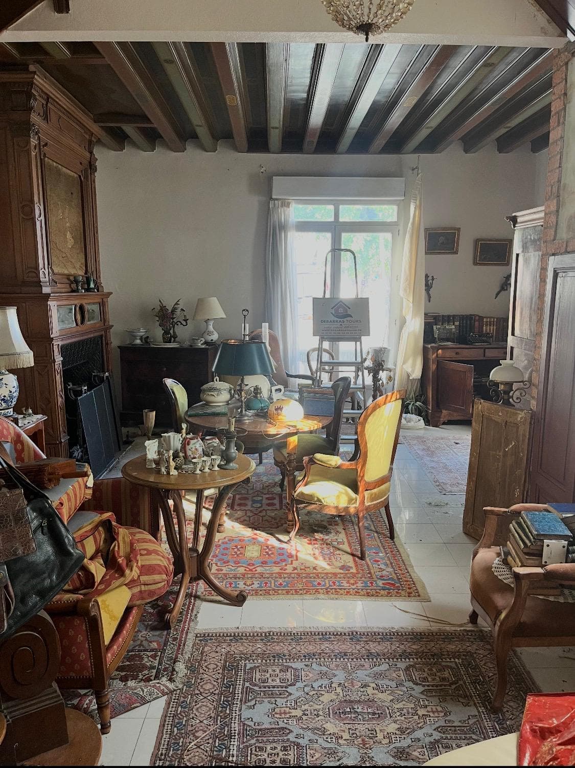 Salon encombré de meubles anciens, tapis et bibelots avant débarras de succession